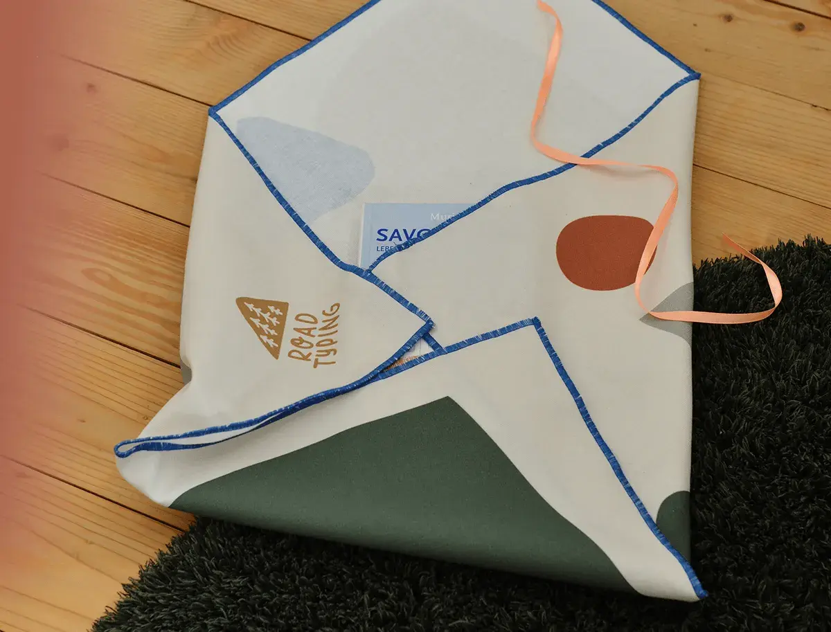 Kreative umschlag verpacken ideen: Stofftuch mit geometrischen Mustern und Schriftzug "Road Typing" wird als Briefumschlag genutzt.