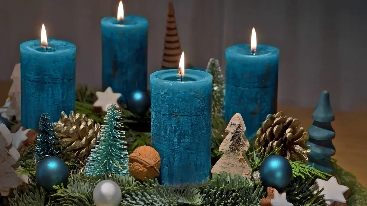 Ein selbstgebastelter Adventskranz mit vier blauen Kerzen, Tannenzweigen, Zapfen und kleinen Bäumchen.