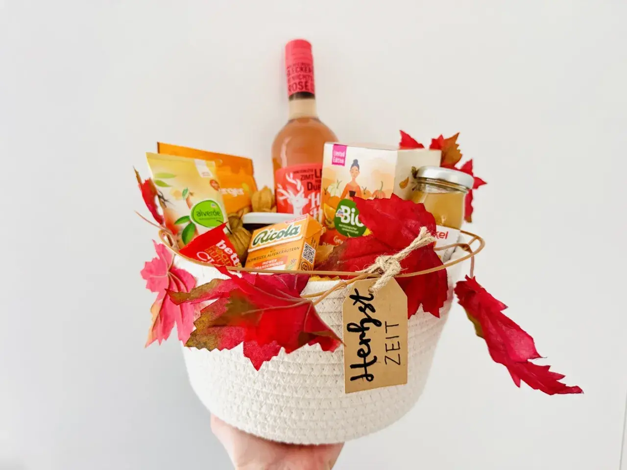 Ein liebevoll gefüllter Geschenkkorb zum Geburtstag, dekoriert mit Herbstlaub. Enthält Wein, Snacks und Honig.