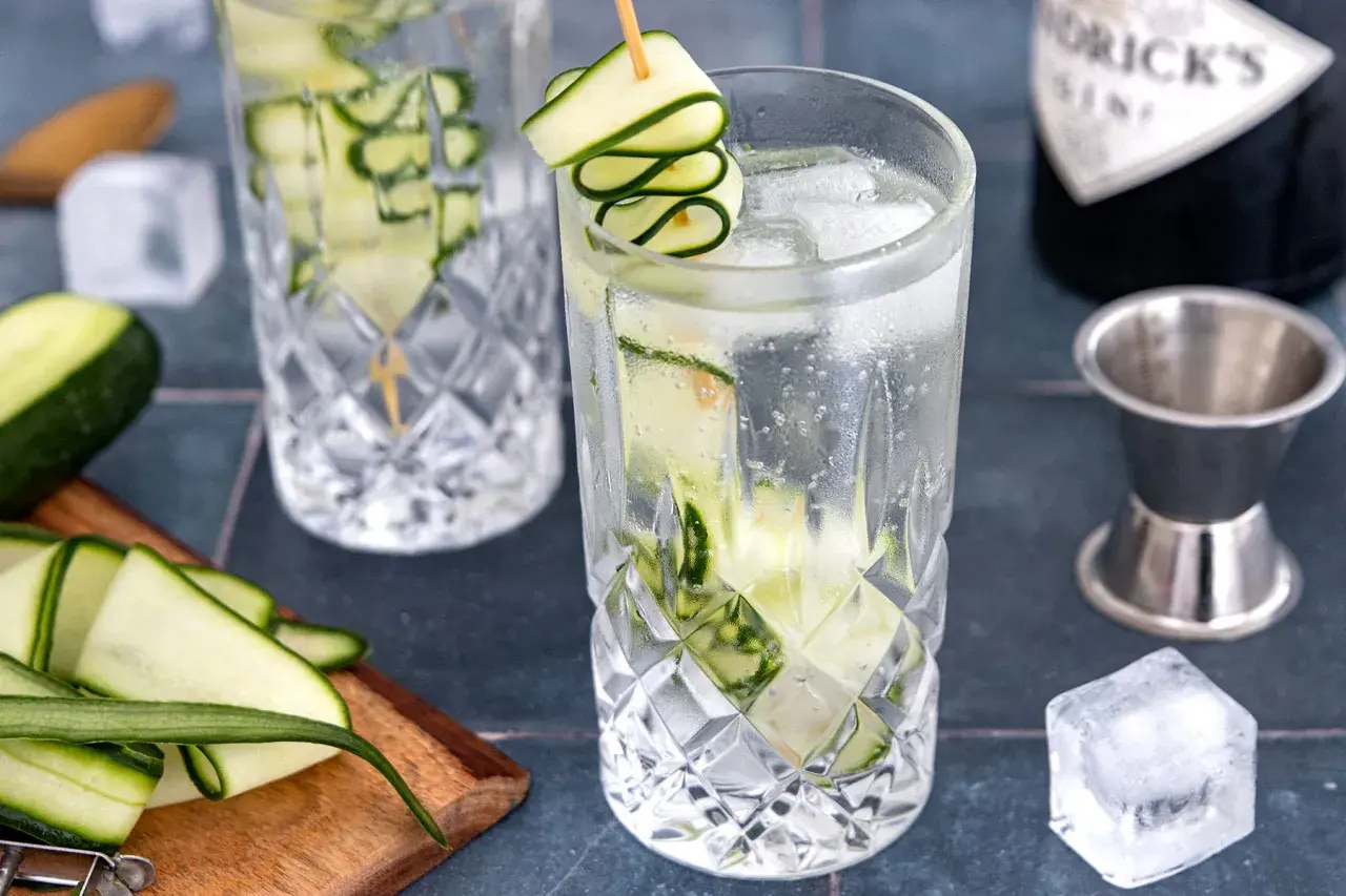Erfrischender Gin mit Gurke, Eiswürfeln und einer dekorativen Gurkenspirale. Perfekt für einen warmen Sommertag.