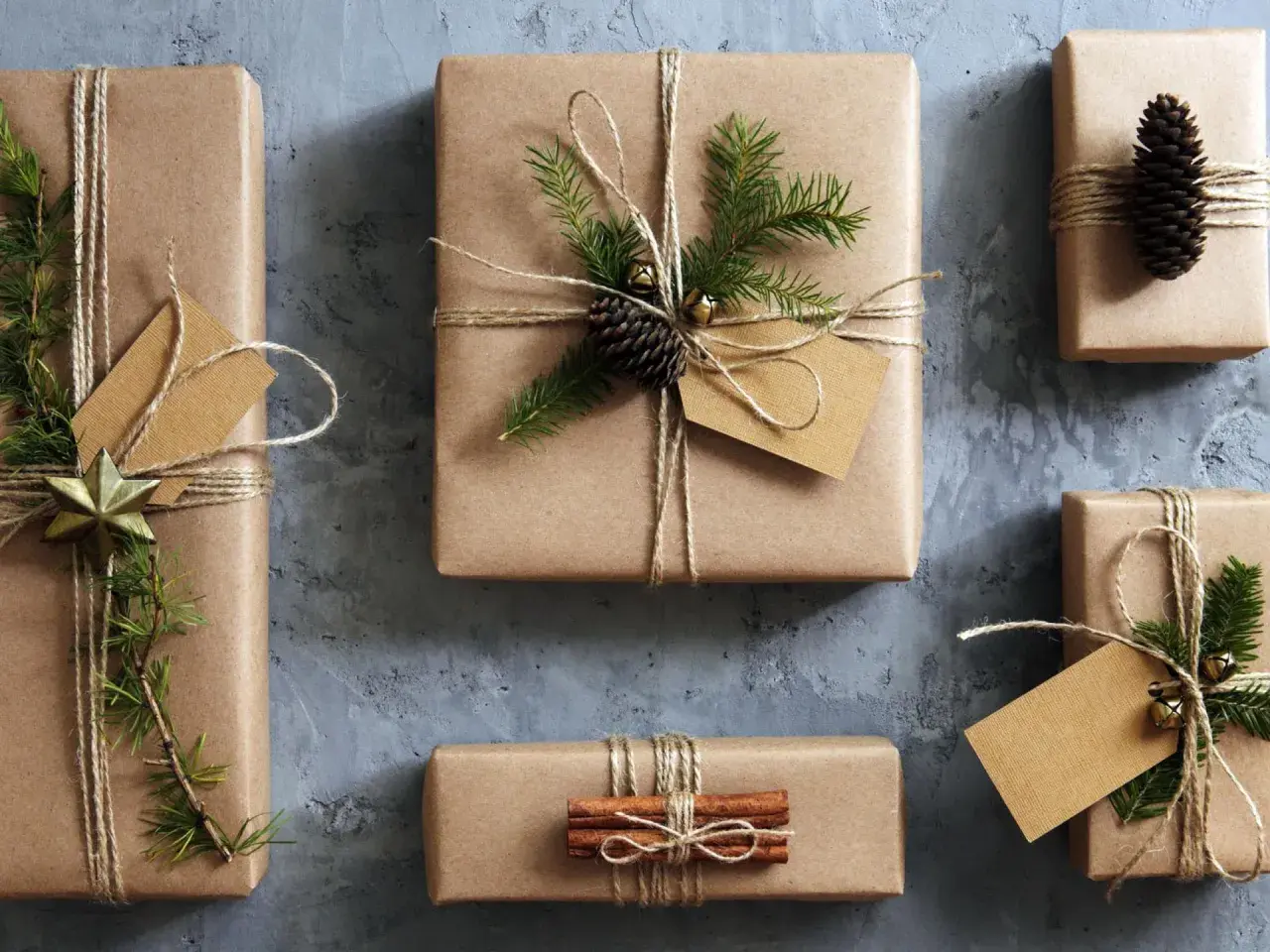Geschenke mit Packpapier verpacken: liebevoll dekorierte Päckchen mit Tannenzweigen, Zapfen und Zimtstangen.