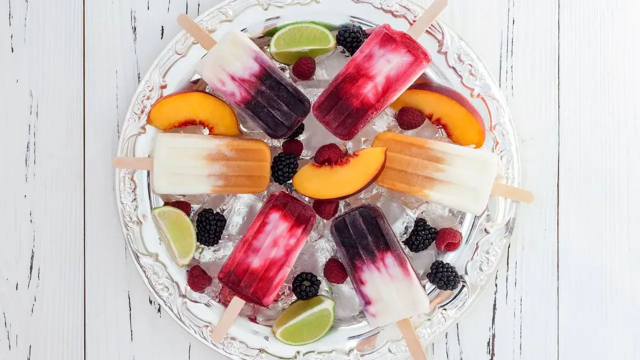 Fruchtige Eis am Stiel mit Beeren, Pfirsich und Limette auf Eis. Ein erfrischender Genuss, der an eis mit Alkohol erinnert.