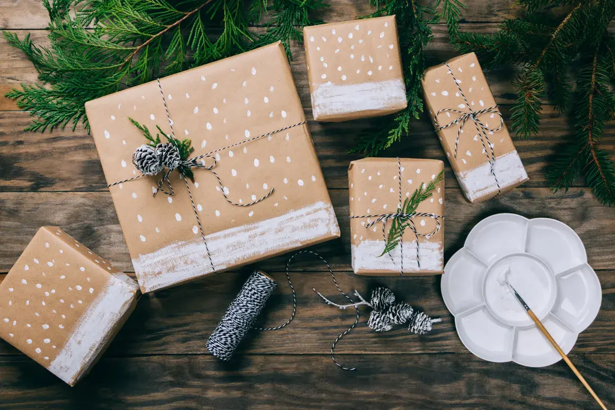 Geschenkpapier bemalen für einen Geburtstag: Geschenke mit weißen Punkten und Tannenzweigen, bereit zum Verschenken.
