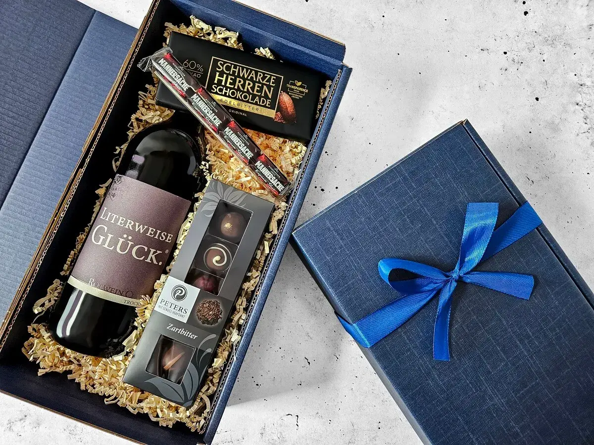 Ein edler Geschenkkorb zum 50. Geburtstag für einen Mann: Rotwein, dunkle Schokolade und Pralinen.