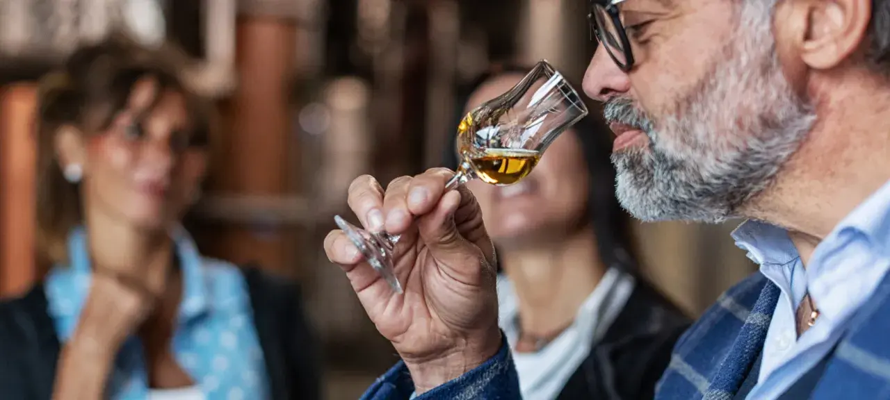 Mann mit Bart schnuppert an einem Grappa-Glas. So trinkt man Grappa: erst riechen, dann genießen.