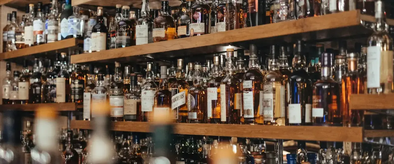 Regale voller Flaschen mit bernsteinfarbenem Whisky oder Whiskey. Eine große Auswahl für Kenner.