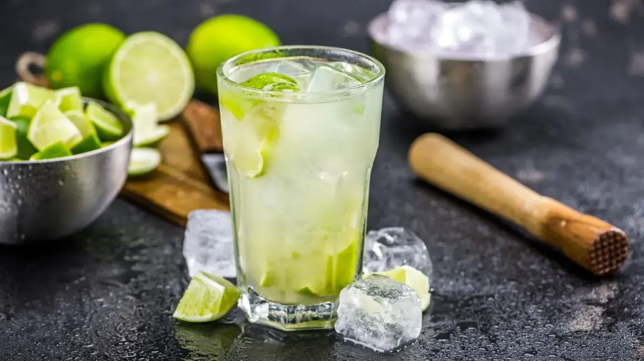 Erfrischende Caipirinha-Varianten mit frischen Limetten, Eis und einem Mörser.