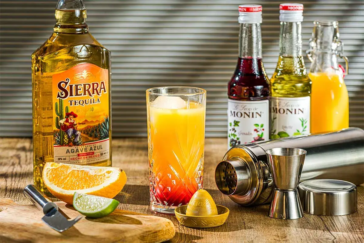 Für einen Tequila Sunrise welcher Tequila? Sierra Tequila Reposado, Orangensaft, Grenadine-Sirup und Limette sind bereit für den Drink.