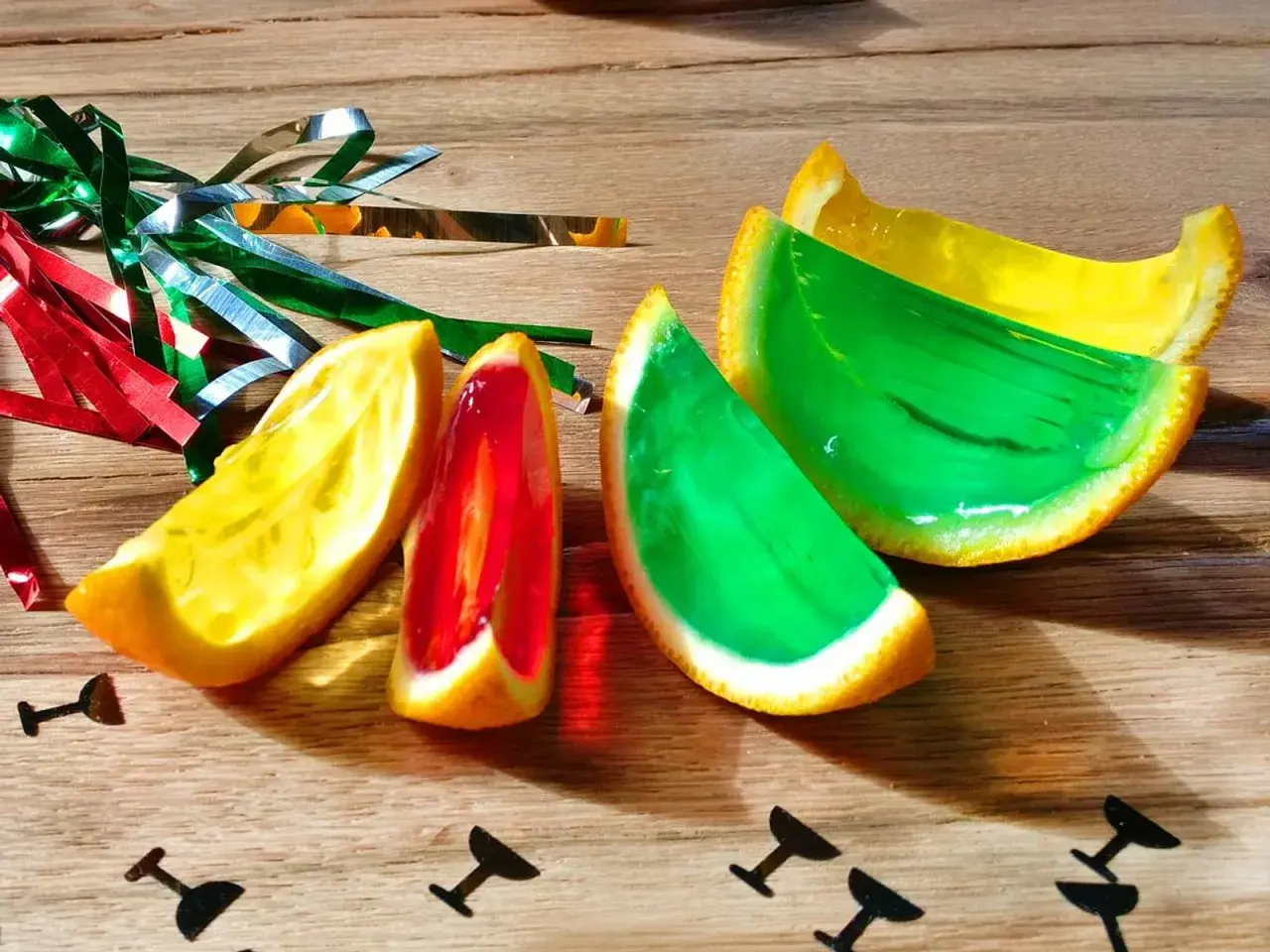 Farbige Jelly Shots in Orangenschalen, dekoriert mit Party-Konfetti. Ein süßer Genuss für jede Feier!