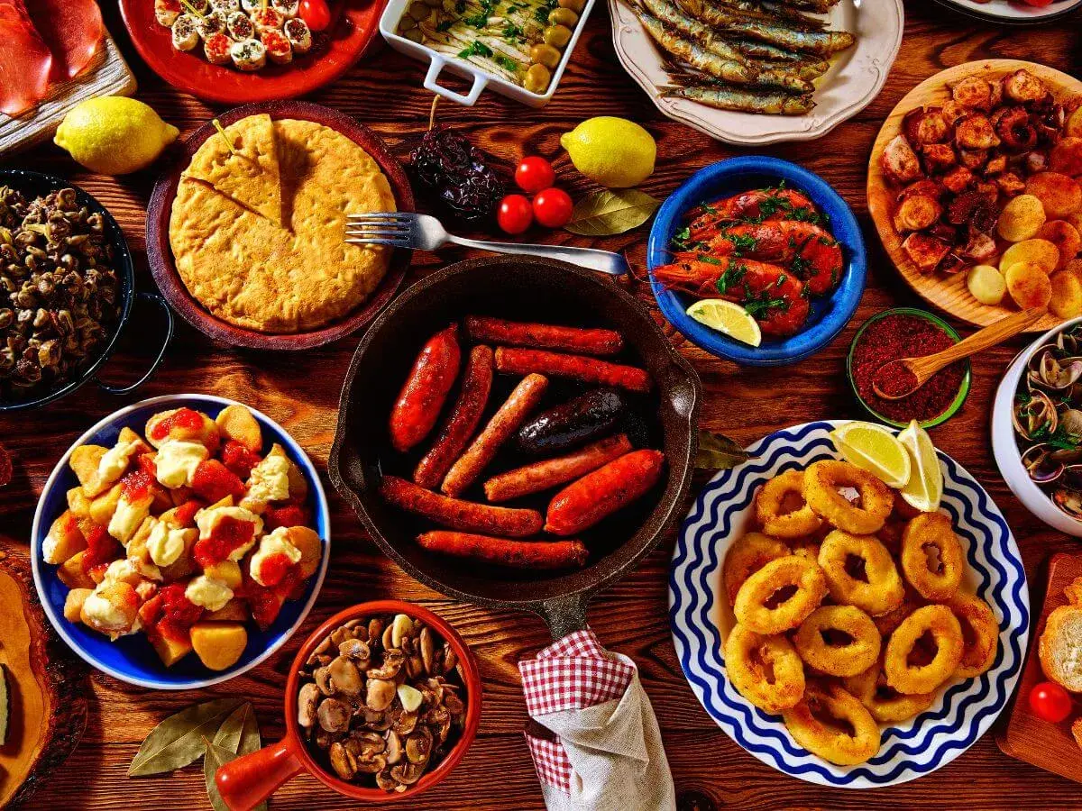 Vielfältige Tapas-Auswahl, perfekt für einen selbstgemachten Geschenkkorb: Chorizo, Garnelen, Calamari, Patatas Bravas und mehr.