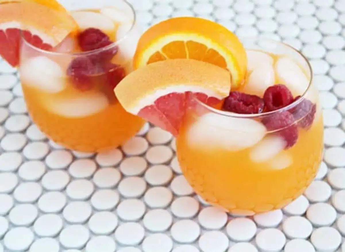 Zwei erfrischende Aperol Lillet Cocktails mit Himbeeren und Zitrusfrüchten auf einem Mosaik-Tisch.
