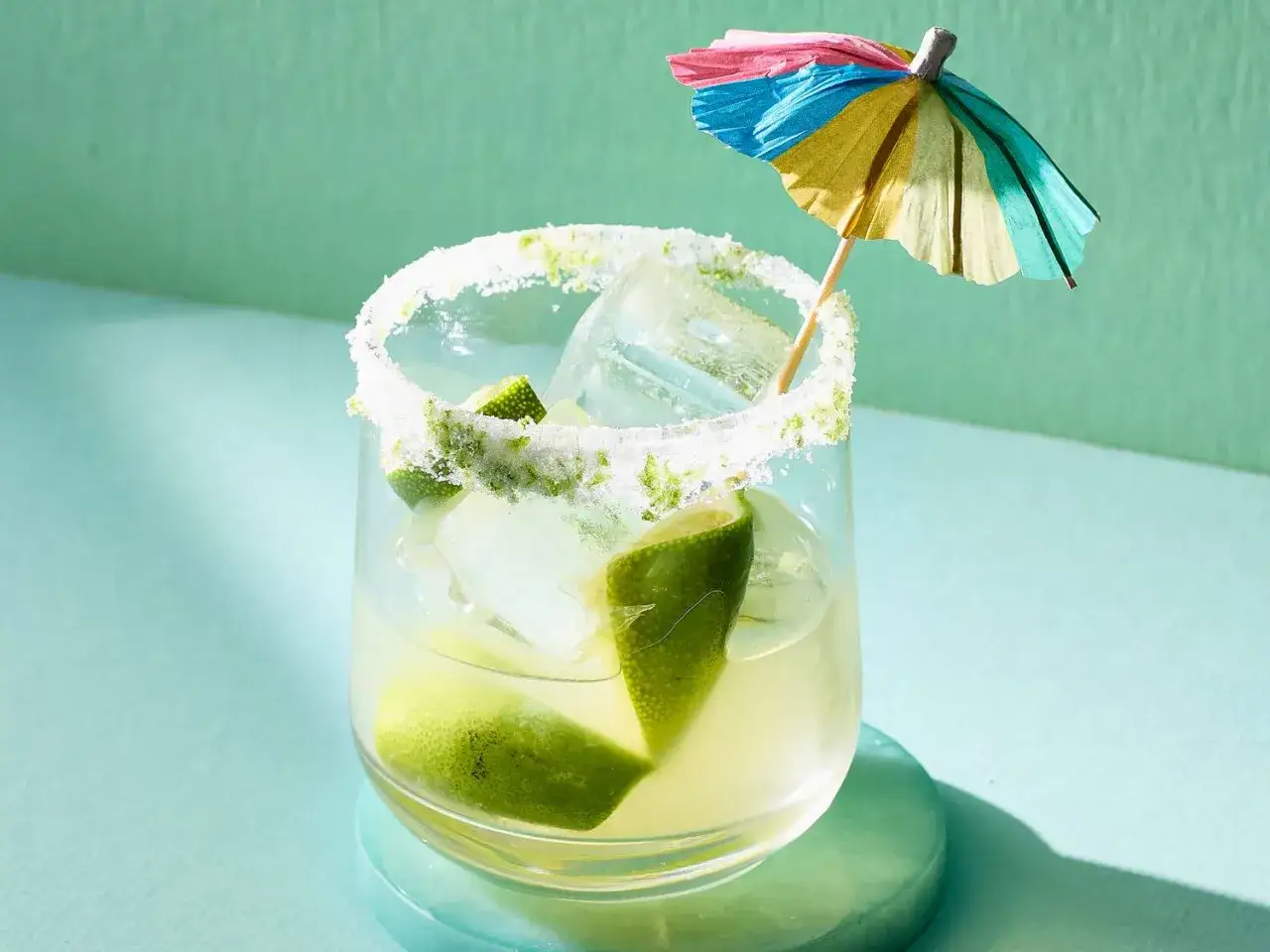 Erfrischende Caipirinha-Varianten mit Limette, Eis und einem bunten Schirmchen.