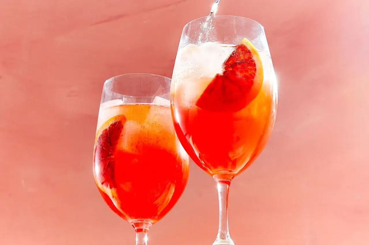 Zwei Gläser Campari Spritz mit Orangenscheiben und Eis, erfrischend und leuchtend rot.