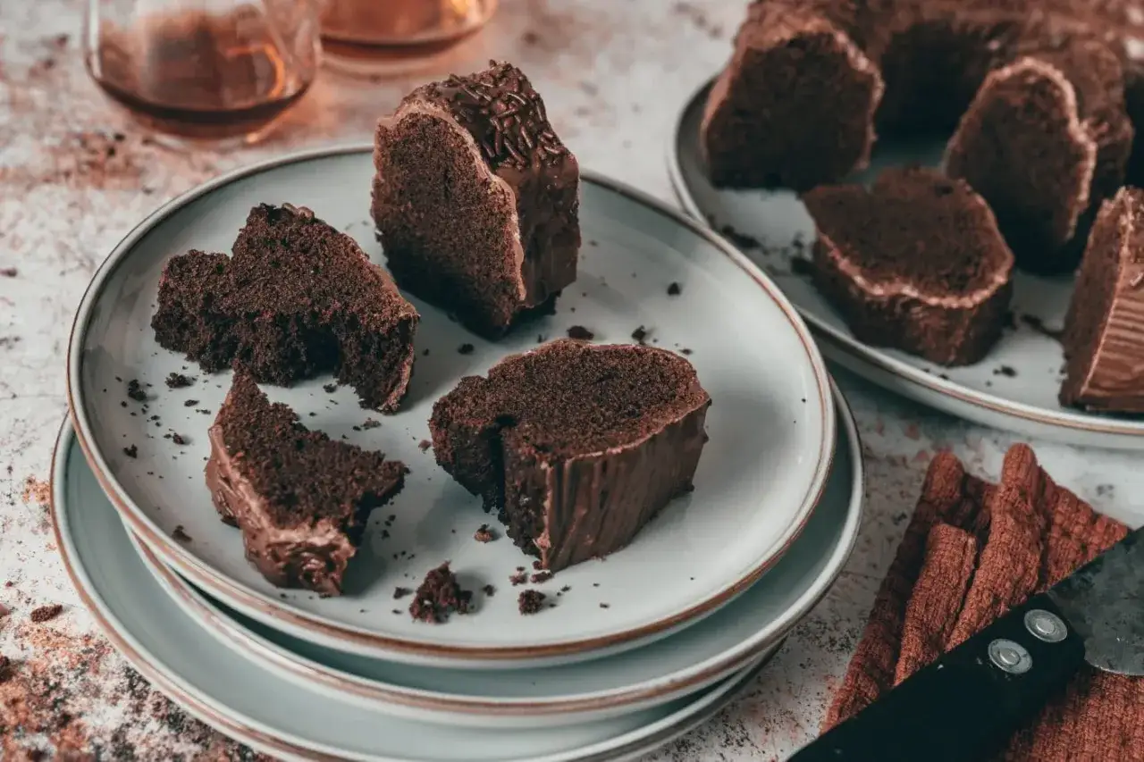 Schokoladenkuchenstücke auf Tellern, bereit zum Genießen. Ein Stück ist mit Schokostreuseln verziert. Perfekt zum rum backen und genießen.