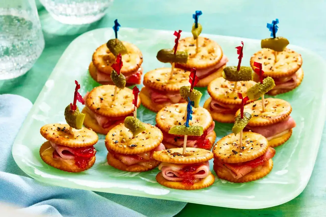 Kleine Sandwiches auf Crackern mit Schinken und Marmelade, garniert mit Gewürzgurken. Perfekte schnelle Partysnacks zum Vorbereiten!