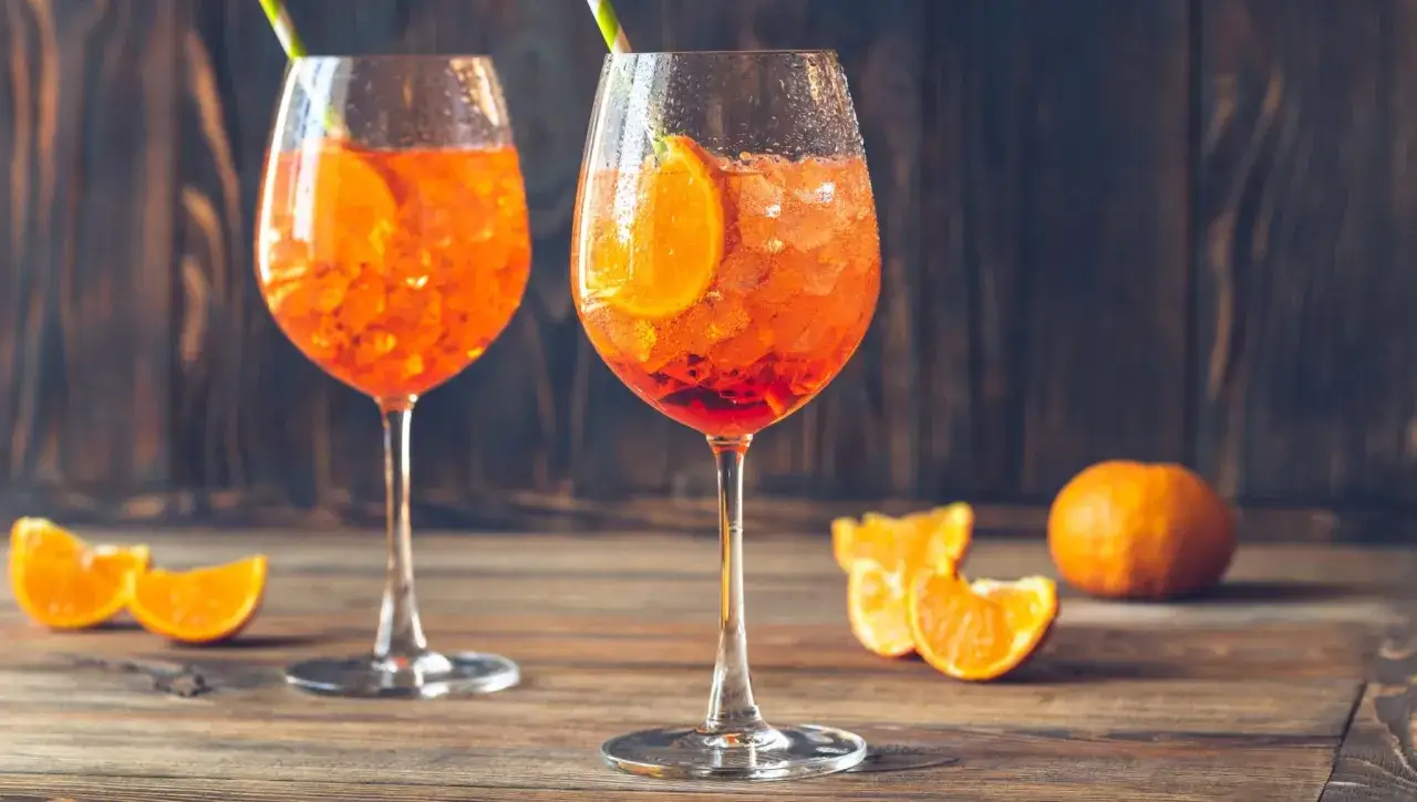 Zwei Gläser Aperol Spritz mit Orangenscheiben und Eis, bereit zum Aperol mischen.