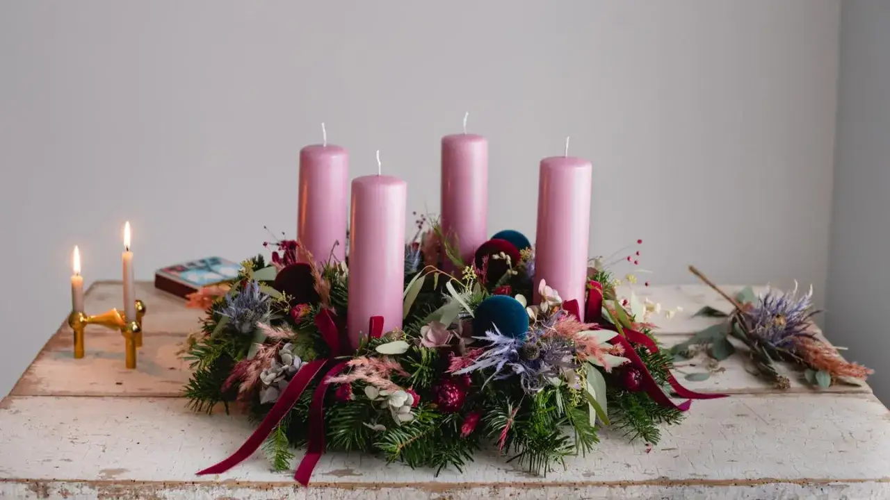 Ein wunderschöner Adventskranz natur selber machen: vier rosa Kerzen auf Tannengrün, dekoriert mit Trockenblumen und Samtband.