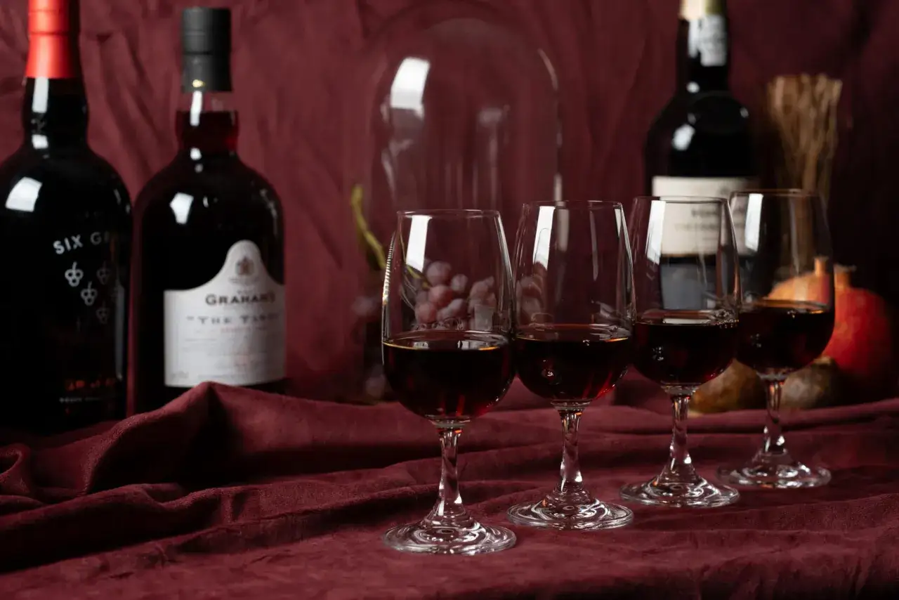 Drei Gl&auml;ser mit dunklem Portwein stehen vor Flaschen. Der intensive Portwein Geschmack verspricht ein vollmundiges Erlebnis.