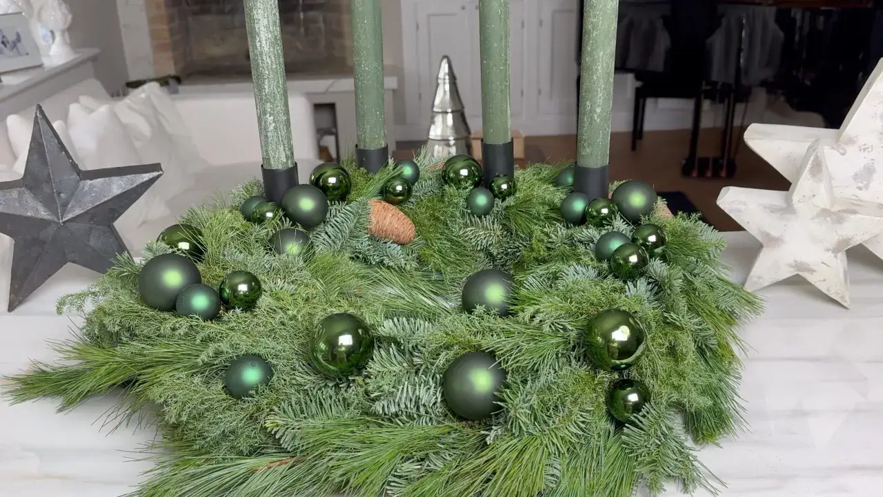 Ein grüner Adventskranz mit vier Kerzen, geschmückt mit Kugeln und Tannenzapfen. Perfekt, um einen weihnachtskranz selber basteln.