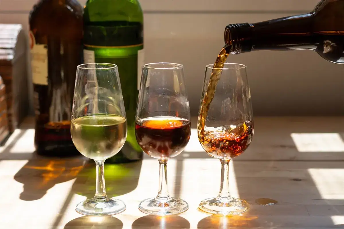 Drei Gl&auml;ser mit Sherry Aperitif, eines wird gerade nachgef&uuml;llt.