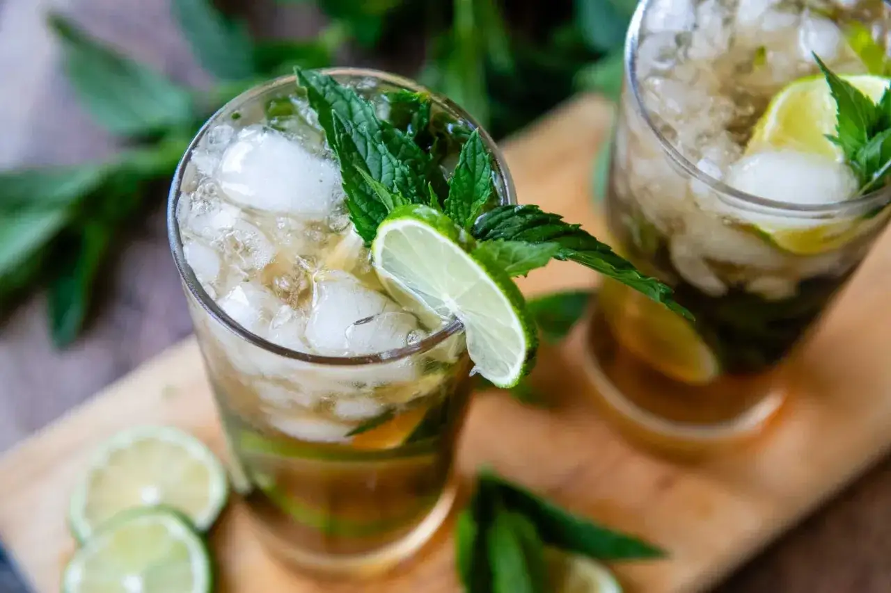Erfrischender Mojito mit braunem Rum, Limette und Minze, serviert mit viel Eis.